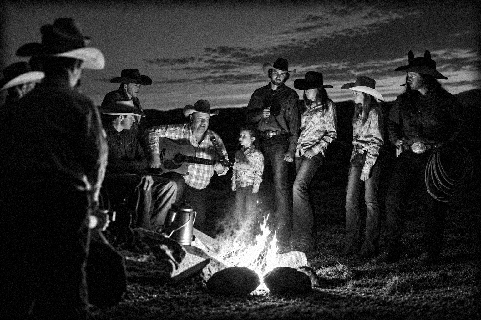 Familias reunidas alrededor de la fogata con guitarra