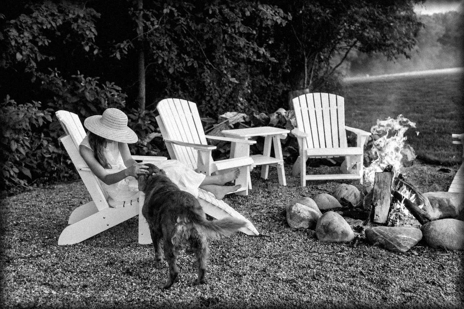 Niña con sombrero y su perro junto a la fogata