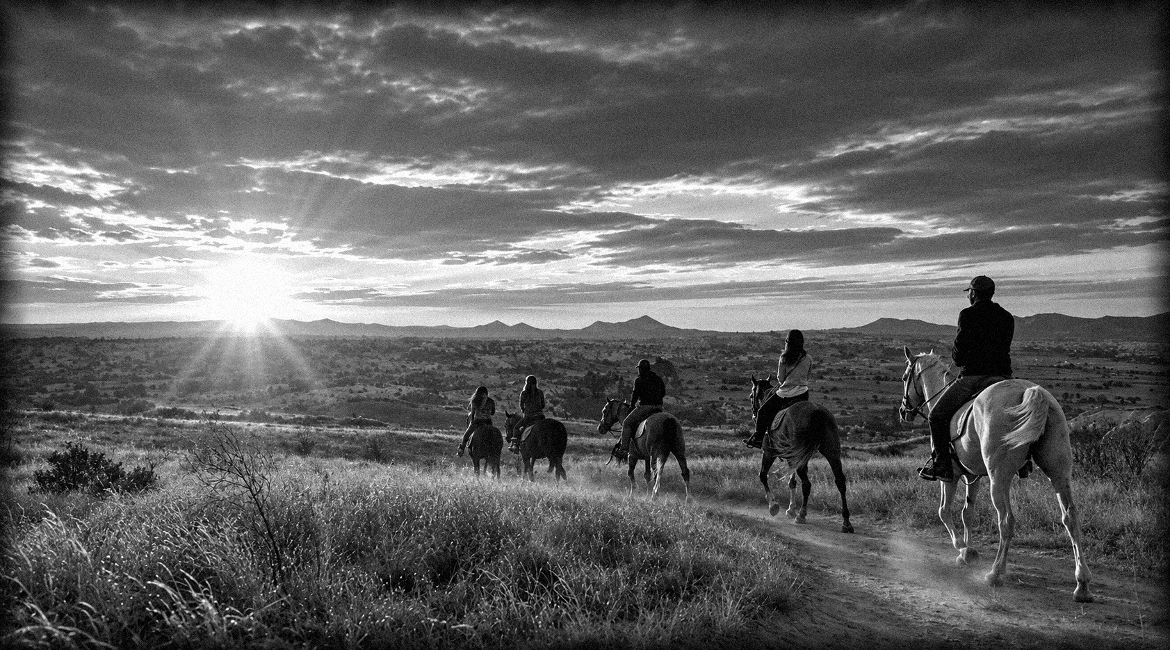 Familia cabalgando hacia el atardecer por el campo abierto